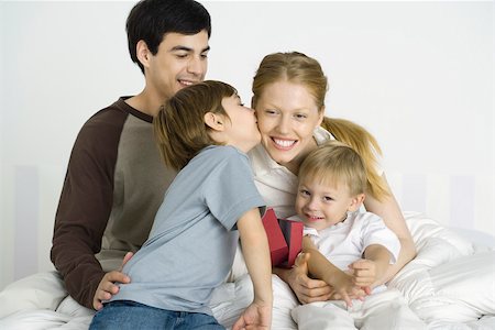 simsearch:632-05816381,k - Family sitting together on bed, boy kissing mother's cheek Stock Photo - Premium Royalty-Free, Code: 695-03390197
