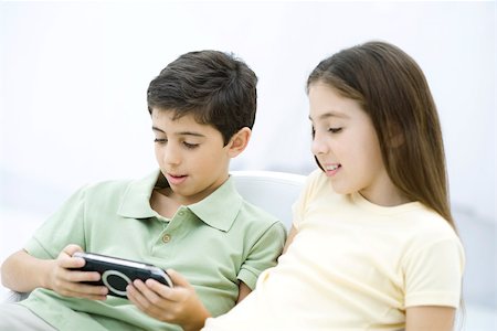 simsearch:632-03424261,k - Brother and sister sitting together, boy playing handheld video game Stock Photo - Premium Royalty-Free, Code: 695-03390257