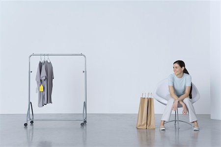 silhouette of human hanging - Woman sitting with shopping bags, looking at tee-shirts on nearby rack Stock Photo - Premium Royalty-Free, Code: 695-03390276