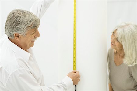 Senior couple smiling at each other, man holding up measuring tape Stock Photo - Premium Royalty-Free, Code: 695-03390319