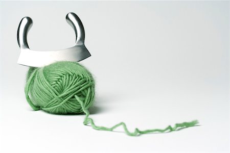 Mincing knife cutting into skein of green yarn Stock Photo - Premium Royalty-Free, Code: 695-03390398