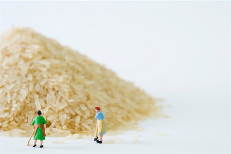 Miniature women sweeping up giant pile of rice Stock Photo - Premium Royalty-Free, Code: 695-03390442