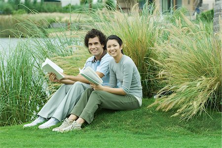simsearch:633-01715612,k - Couple sitting on grass with books, smiling at camera Stock Photo - Premium Royalty-Free, Code: 696-03394227