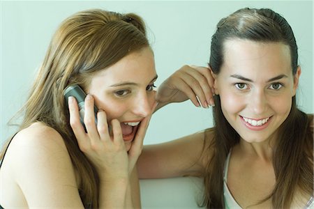 simsearch:640-03260747,k - Two young friends smiling together, using cell phone, one looking at camera Stock Photo - Premium Royalty-Free, Code: 696-03394288