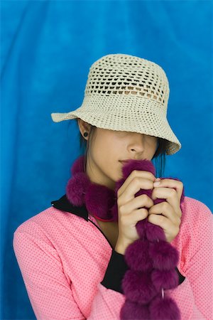 Teenage girl with hat covering eyes, holding boa, portrait Stock Photo - Premium Royalty-Free, Code: 696-03394999