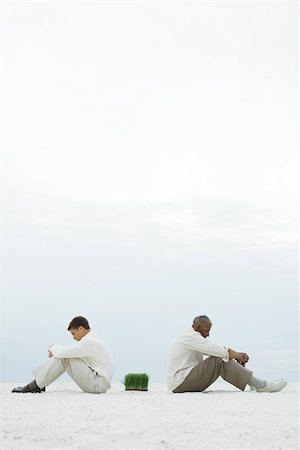 separate - Two men sitting back to back at the beach, wheat grass between them, side view Stock Photo - Premium Royalty-Free, Code: 696-03395223