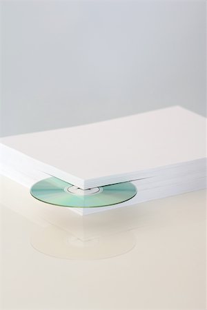 poking - Stack of paper with CD emerging from the corner Stock Photo - Premium Royalty-Free, Code: 696-03396037