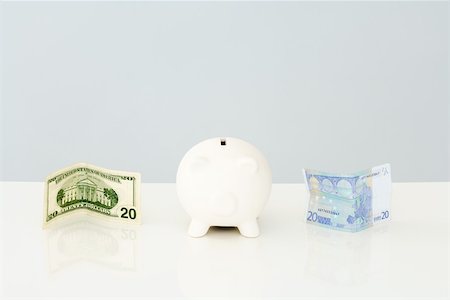 simsearch:400-07218287,k - Piggy bank with folded twenty dollar bill to one side and a twenty euro bill on the other side Stock Photo - Premium Royalty-Free, Code: 696-03396044
