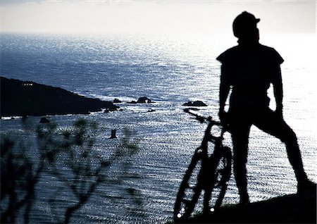 silhouette bike - Cyclist looking at the sea, rear view, silhouette Stock Photo - Premium Royalty-Free, Code: 696-03397008