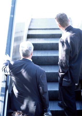 Businessmen riding escalator, rear view. Stock Photo - Premium Royalty-Free, Code: 696-03397361