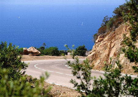 simsearch:400-04636750,k - France, Corsica, road curving around mountain, sea in background. Stock Photo - Premium Royalty-Free, Code: 696-03397462