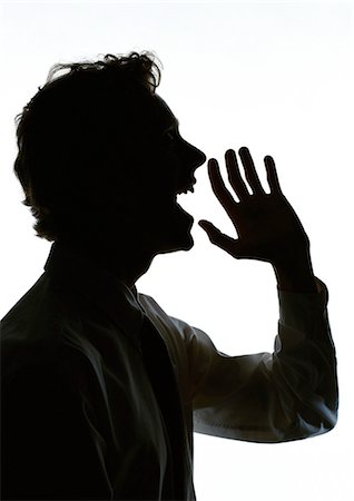 Man yelling with hand out in front of mouth, silhouette Stock Photo - Premium Royalty-Free, Code: 696-03397928