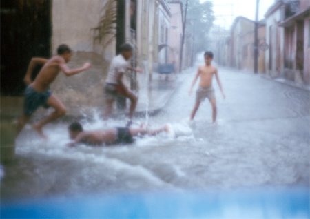 Boys running in waterlogged street, one lying down on ground, blurred Stock Photo - Premium Royalty-Free, Code: 696-03398640