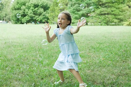 ruffle (gathered pleats) - Girl reaching for bubbles Stock Photo - Premium Royalty-Free, Code: 696-03393964