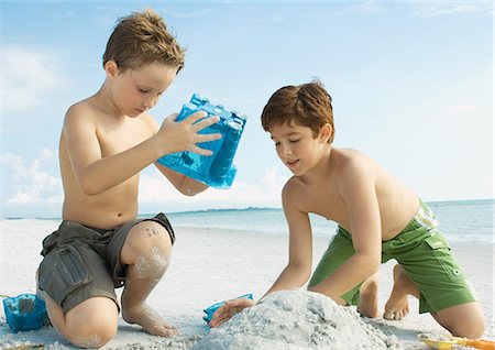 Boys building sand castle on the beach Stock Photo - Premium Royalty-Free, Code: 696-03400803