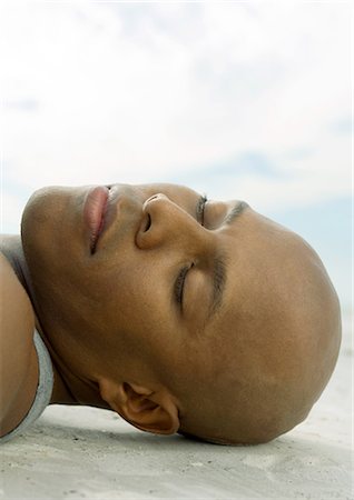 Man lying on sand with eyes closed, close-up of head Stock Photo - Premium Royalty-Free, Code: 696-03400849