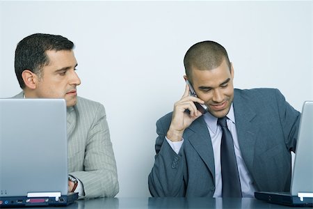 simsearch:695-03376228,k - Two businessmen using laptops, one using cell phone while other watches him Stock Photo - Premium Royalty-Free, Code: 696-03401169