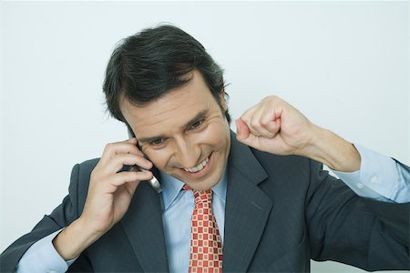 simsearch:695-03376228,k - Businessman using cell phone, smiling, and making fist Stock Photo - Premium Royalty-Free, Code: 696-03401173