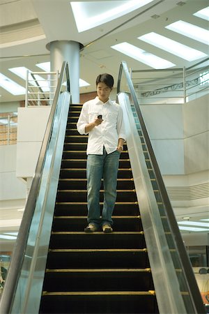 Man on escalator checking cell phone Foto de stock - Sin royalties Premium, Código: 696-03401245