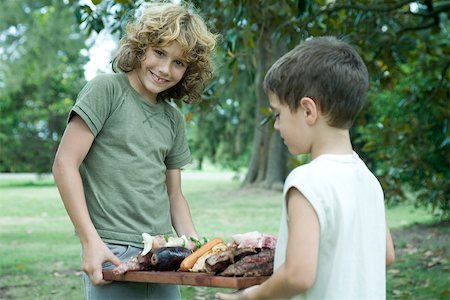Two boys holding tray of grilled meats Stock Photo - Premium Royalty-Free, Code: 696-03401433