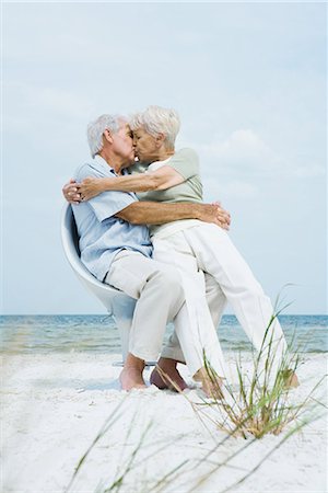 stalemate - Senior couple sitting in chair together on beach, hugging and kissing, woman sitting on man's lap, full length Foto de stock - Sin royalties Premium, Código: 696-03401981