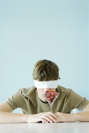 enigma - Teen boy wearing blindfold, smelling glass full of cherries Stock Photo - Premium Royalty-Free, Code: 696-03402167