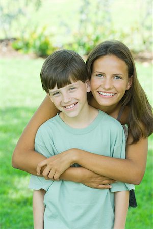 sister brother hugging two - Teenage girl and younger brother smiling at camera together, portrait Stock Photo - Premium Royalty-Free, Code: 696-03402217