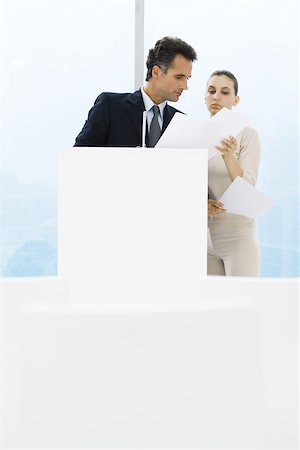 simsearch:632-05604064,k - Businessman standing by lectern, female assistant holding up documents for him Stock Photo - Premium Royalty-Free, Code: 696-03402404