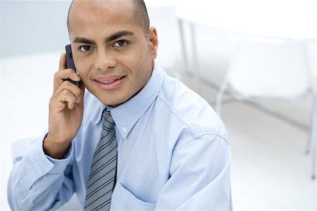 simsearch:695-03376228,k - Businessman using cell phone, smiling at camera Stock Photo - Premium Royalty-Free, Code: 696-03402453