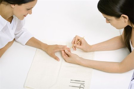 fussy - Woman receiving manicure, looking down at hand, cropped view Stock Photo - Premium Royalty-Free, Code: 696-03402619