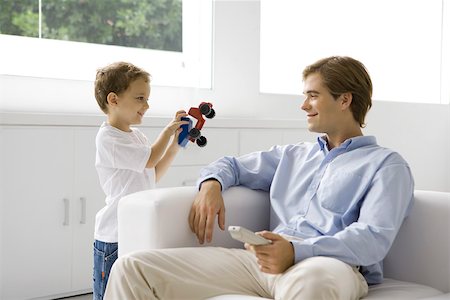 Little boy showing his father a toy truck, man holding remote control Stock Photo - Premium Royalty-Free, Code: 696-03402644