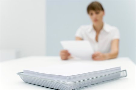 entry field - Stack of paper in metal tray, woman reading document in background Stock Photo - Premium Royalty-Free, Code: 696-03402666
