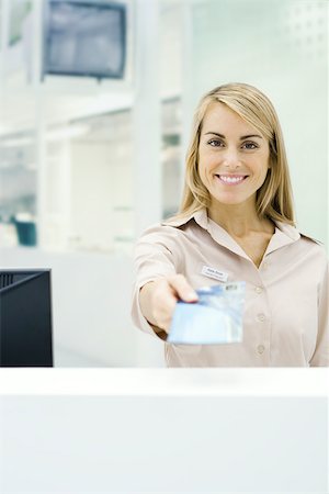 Travel agent holding out ticket, smiling at camera, personal perspective Stock Photo - Premium Royalty-Free, Code: 696-03402790