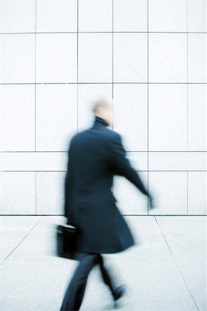 Businessman hurrying down sidewalk Stock Photo - Premium Royalty-Free, Code: 696-03402932