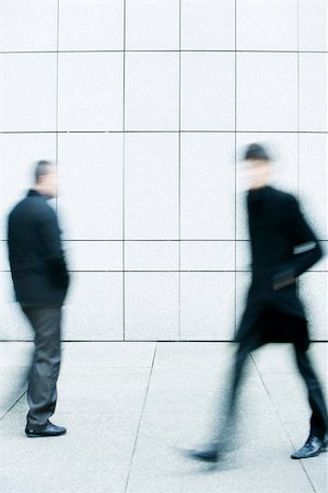 Two men passing one another as they walk along the sidewalk Stock Photo - Premium Royalty-Free, Code: 696-03402971