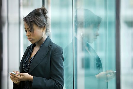 Businesswoman using cell phone, looking down Stock Photo - Premium Royalty-Free, Code: 696-03403005