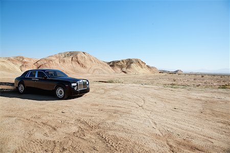 Rolls Royce car leaving trail of black oil behind on unpaved road Stock Photo - Premium Royalty-Free, Code: 693-05552682