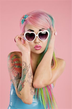simsearch:693-05552824,k - Young woman posing wearing sunglasses over pink background Stock Photo - Premium Royalty-Free, Code: 693-05552798