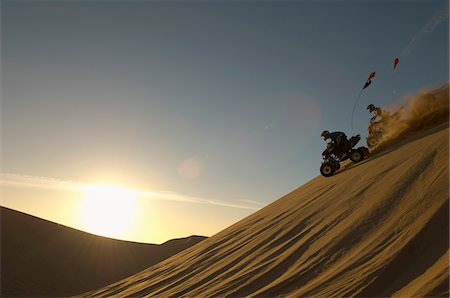 Men riding quad bikes in desert at sunset Stock Photo - Premium Royalty-Free, Code: 693-06015642