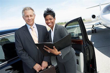 Businesspeople standing in door of car on landing strip near private jet Stock Photo - Premium Royalty-Free, Code: 693-06016938