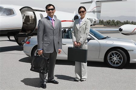 Portrait of mid-adult businesswoman and mid-adult businessman standing in front of private plane on landing strip. Stock Photo - Premium Royalty-Free, Code: 693-06016967