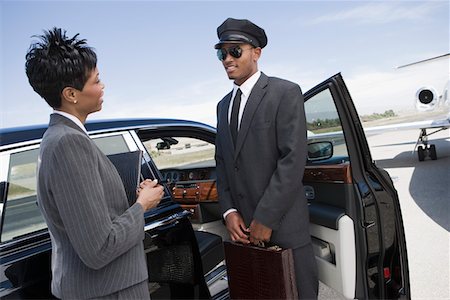 Mid-adult businesswoman and mid-adult chauffeur standing  in front of limousine and talking. Stock Photo - Premium Royalty-Free, Code: 693-06016970