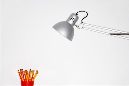 Angle poise lamp shining on cup of pencils Stock Photo - Premium Royalty-Free, Code: 693-06018802