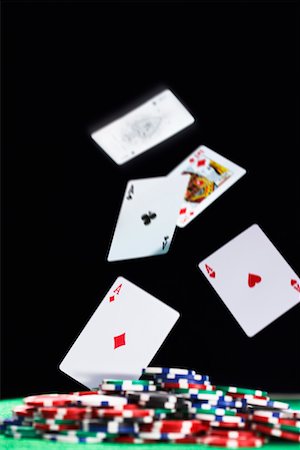 poker game - Playing cards falling on pile of gambling chips, in studio Stock Photo - Premium Royalty-Free, Code: 693-06018923