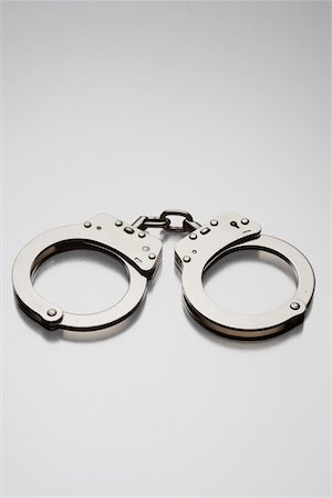 restraint - Handcuffs on white background in studio Stock Photo - Premium Royalty-Free, Code: 693-06018940