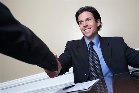 Business man shaking hands with colleague at desk in office Stock Photo - Premium Royalty-Free, Code: 693-06019595