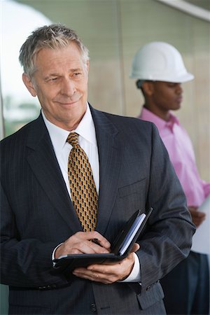 day calendar with plans - Businessman holding day planner with construction worker behind Stock Photo - Premium Royalty-Free, Code: 693-06019718