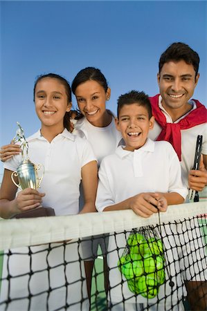 simsearch:693-06013834,k - Tennis Family at net on tennis court, daughter holding trophy, portrait Stock Photo - Premium Royalty-Free, Code: 693-06013835