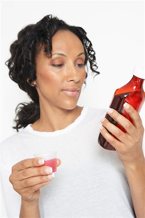 sick black woman - Woman holding medicine, reading bottle, studio shot Stock Photo - Premium Royalty-Free, Code: 693-06020010