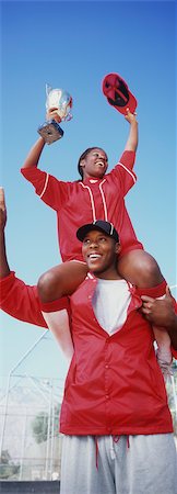 Woman holding trophy, sitting on man's shoulders, low angle view Stock Photo - Premium Royalty-Free, Code: 693-06020102